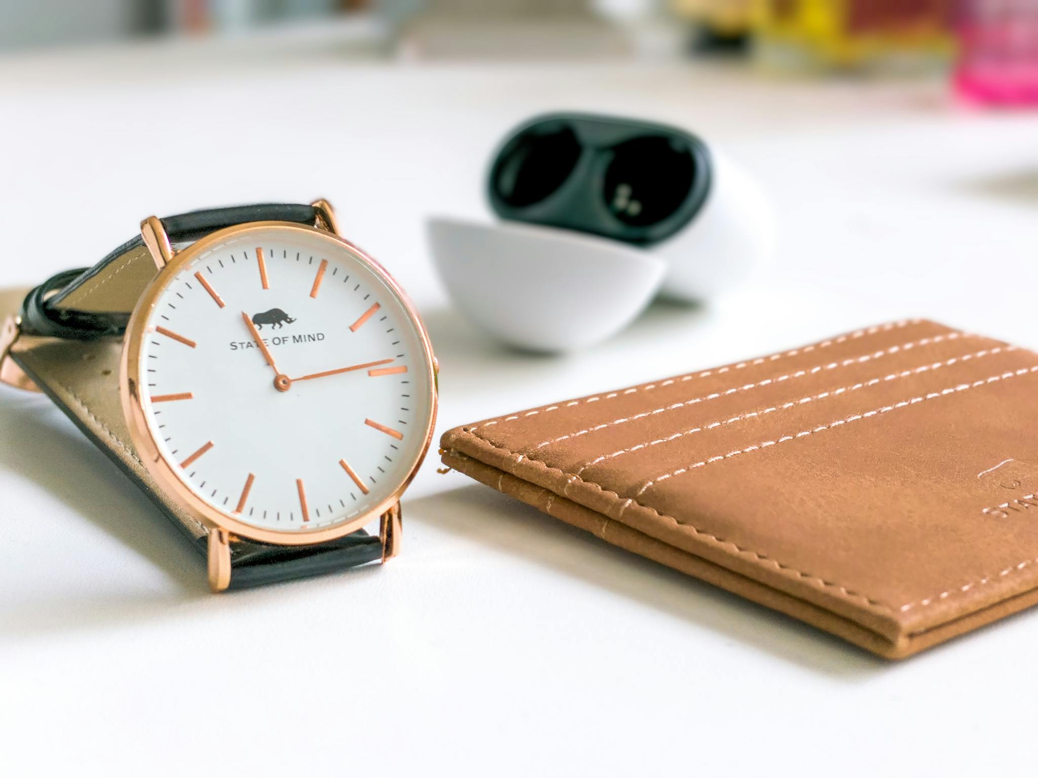 Close-up of a stylish watch, leather card holder, and earphone in a modern setting.